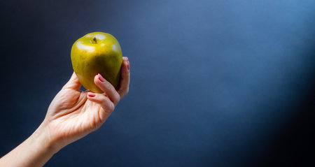 Hand holding green apple on blue background organic natural fresh fruit for vegan diet