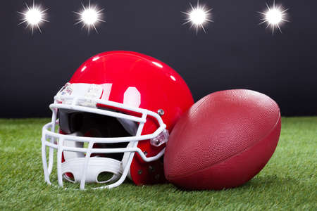 Red sports helmet lying on green grass field