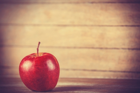 Red apple on wooden table photo in retro color style