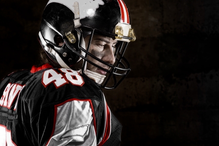 Portrait of thoughtful american football player on dark background Stock Photo