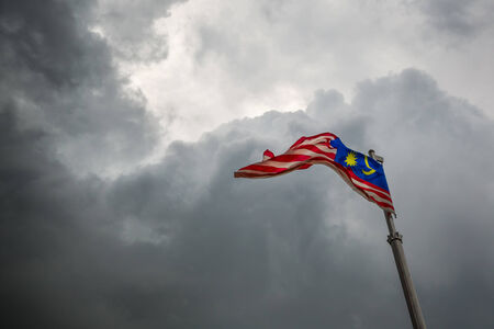 A malaysian flag over a stormy cloud sky