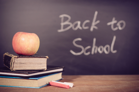 Apple and books on the wooden desk with back to school blackboard background