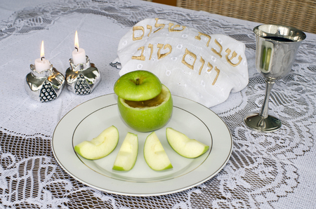 Jewish new year rosh hashanah apple with honey candles challah and wine cup on the seder table