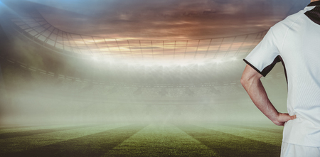 Rear view of rugby player with hands on waist against rugby pitch Stock Photo