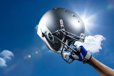 Cropped hand of sportsman holding helmet against sky Stock Photo