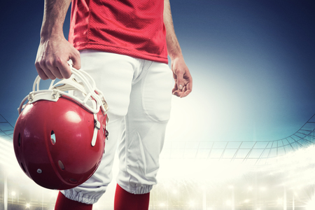 An american football player taking his helmet on her hand against rugby stadium