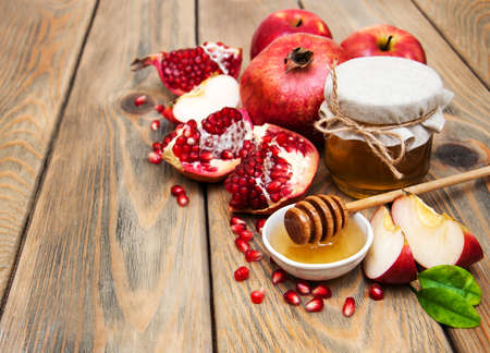 Honey with pomegranate and apples on a old wooden background