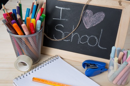 Small school desk with various school supplies close up isolated on white