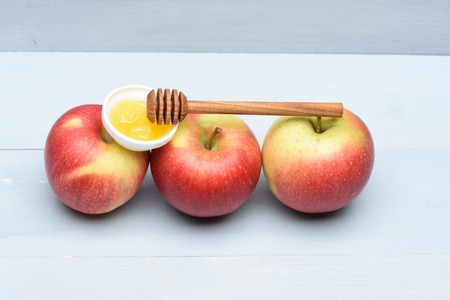 Fresh red apples with honey and honey stick on vintage wooden background Stock Photo