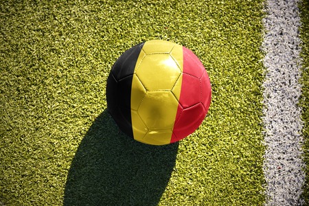 Football ball with the national flag of belgium lies on the green field near the white line Stock Photo