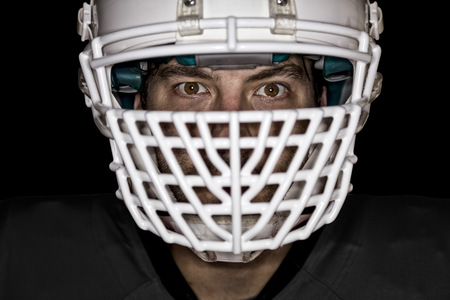 Close up in the eyes of a football player with a black uniform on a black background