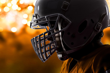 Close up of a football player with a orange uniform on a orange lights background