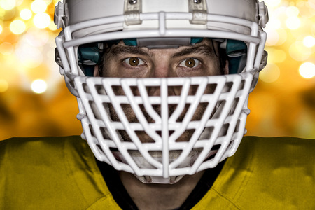 Close up in the eyes of a football player with a yellow uniform on a yellow lights background Stock Photo