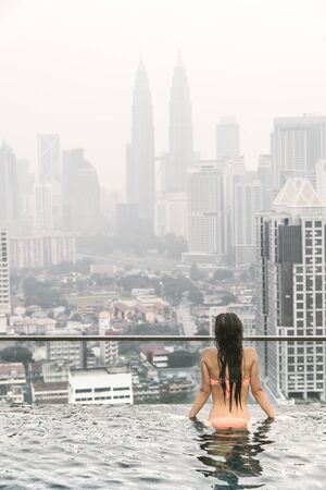 Beautiful woman in swimming pool watching the city kuala lumpur with twin towers