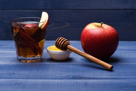 Set of glass with juice pieces of apple cinnamon apple honey honey stick on blue vintage wooden background side view