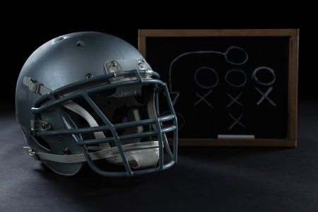 Close up of american football and game strategy drawn on board against black background