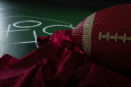 Close up of american football jersey and football lying on green board with strategy drawn on it Stock Photo