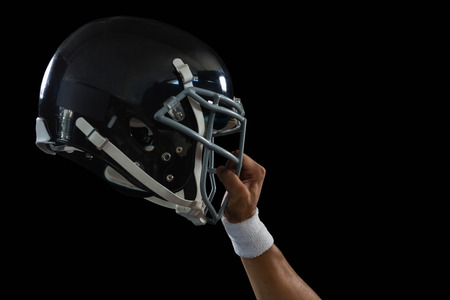 Close up of american football player holding a head gear raised