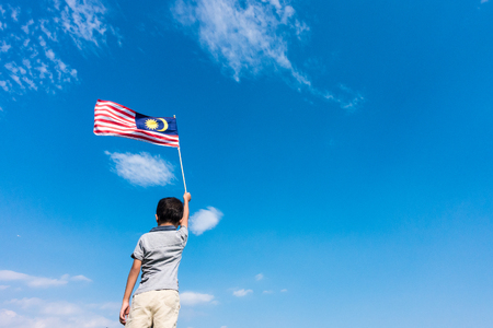 Unknown kid waving malaysia flag independence day and merdeka celebration blue sky and copy space Stock Photo