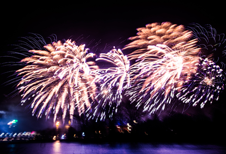 Abstract blurry bokeh style colorful photo of fireworks in a purple tone above the river Stock Photo