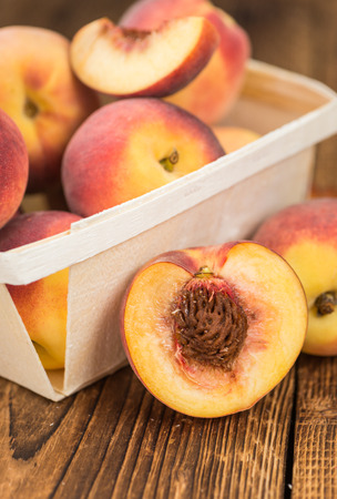 Fresh peaches as high detailed close up shot on a vintage wooden table selective focus