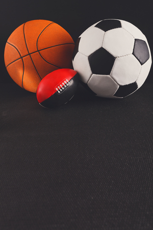 Assorted sports balls on black background tools for playing basketball soccer and football active game healthy lifestyle concept