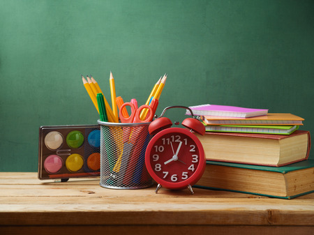 Back to school concept with alarm clock and books on wooden table