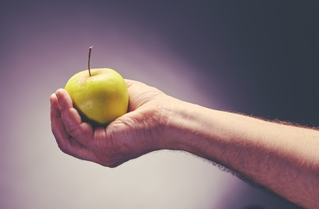 Food and dieting concept male hand holds green apple Stock Photo