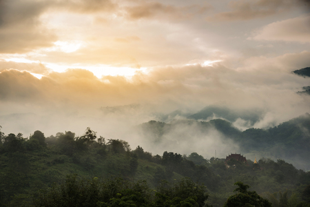 A temple and pagoda on top of beautiful mountains landscape with sunlight clouds and fogs on morning of northern thailand