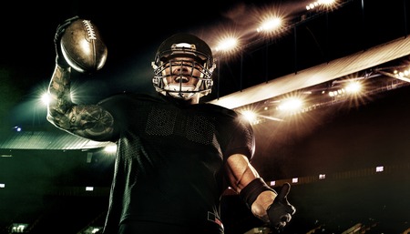 Sport concept american football sportsman player holding ball on stadium