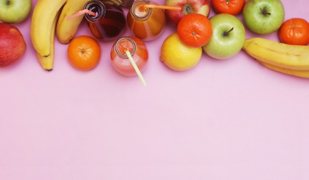 Fruit set on pink background bananas tangerine apples juice bottle space for text